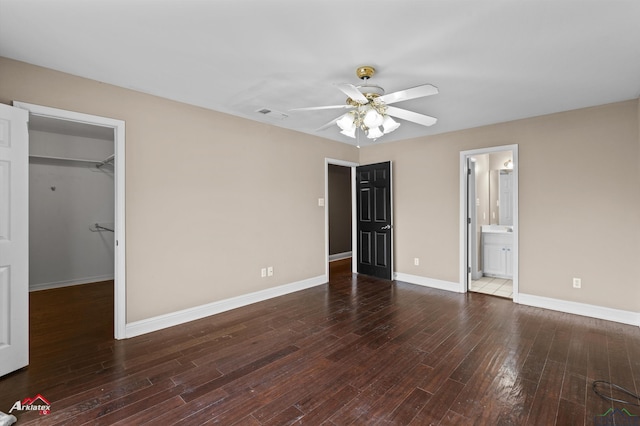 unfurnished bedroom featuring ceiling fan, dark hardwood / wood-style floors, a spacious closet, connected bathroom, and a closet