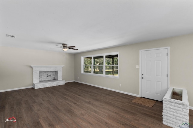 unfurnished living room featuring ceiling fan, dark hardwood / wood-style floors, and a brick fireplace