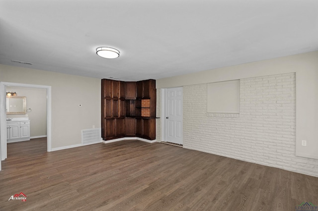 interior space featuring dark hardwood / wood-style floors and brick wall