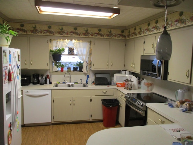 kitchen with light countertops, light wood-style flooring, a sink, white appliances, and a peninsula