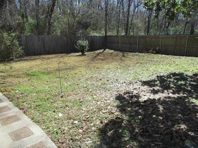 view of yard with a forest view and a fenced backyard