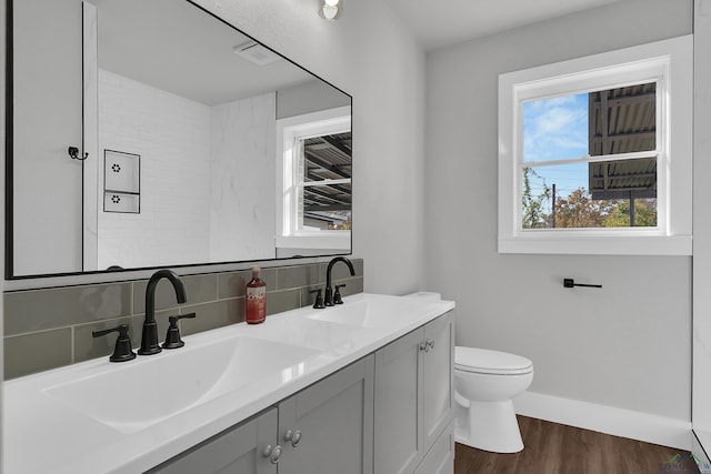 bathroom with hardwood / wood-style floors, vanity, toilet, and tasteful backsplash