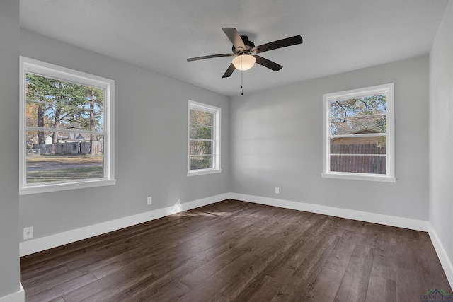 spare room featuring ceiling fan, dark wood-type flooring, and a wealth of natural light