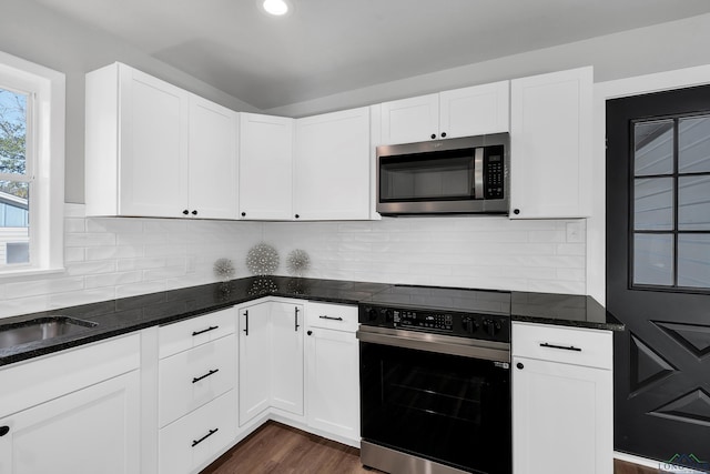 kitchen with dark stone counters, decorative backsplash, white cabinetry, and stainless steel appliances