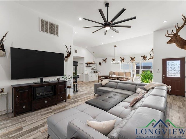 living room featuring ceiling fan, light hardwood / wood-style flooring, and vaulted ceiling