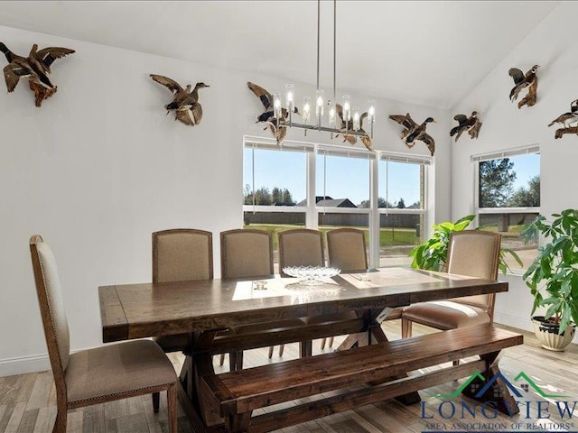 dining space with a chandelier, hardwood / wood-style floors, and vaulted ceiling