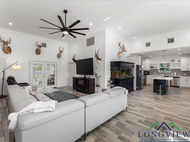 living room with ceiling fan, french doors, and light hardwood / wood-style floors