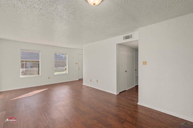 spare room featuring dark hardwood / wood-style flooring and a textured ceiling