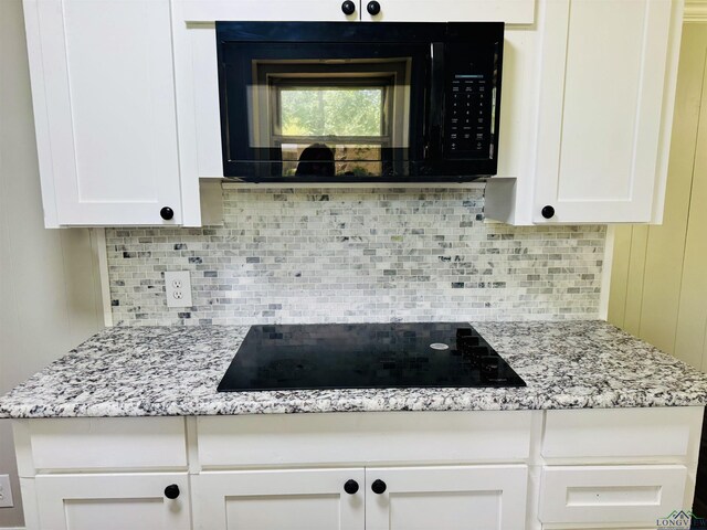2317 Kaynell Dr, Henderson, TX 75654 - kitchen with white cabinetry, backsplash, black appliances, and light stone countertops
