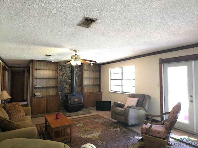 living room with a textured ceiling, a wood stove, and ceiling fan