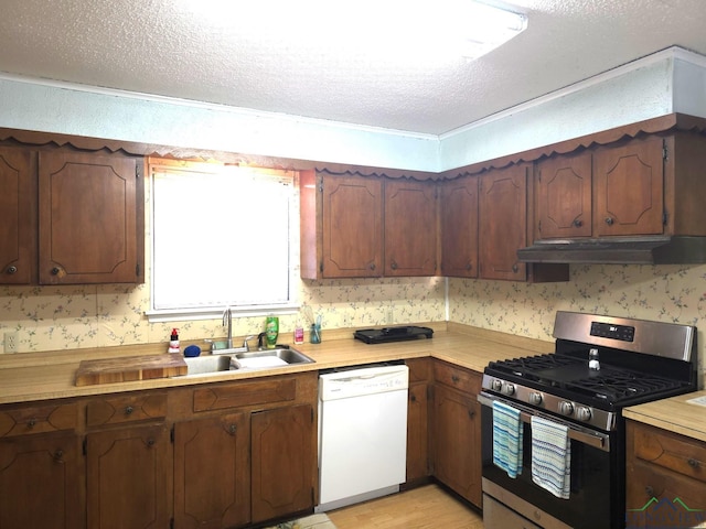 kitchen featuring gas stove, sink, white dishwasher, and a textured ceiling