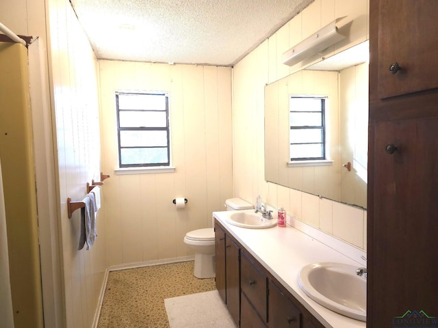 bathroom featuring wood walls, a healthy amount of sunlight, and a textured ceiling