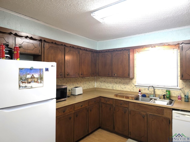 kitchen with a textured ceiling, white appliances, dark brown cabinets, and sink