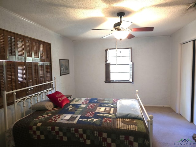 carpeted bedroom with ceiling fan and a textured ceiling