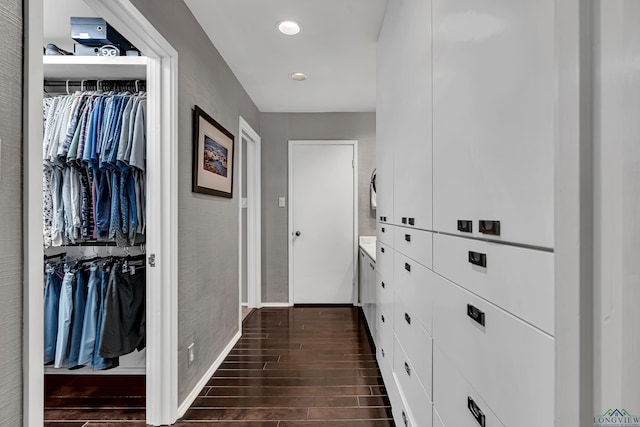 hallway featuring dark wood-type flooring, recessed lighting, and baseboards