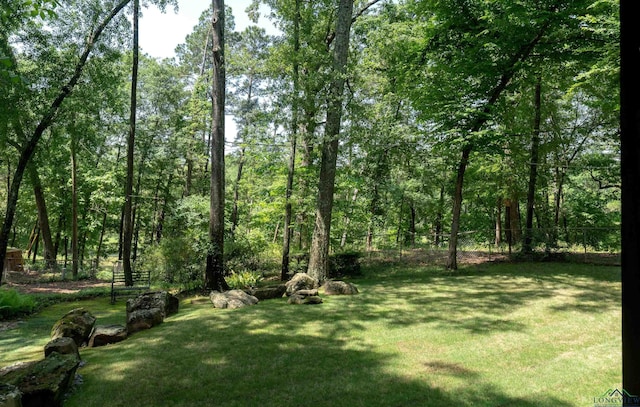 view of yard featuring fence and a wooded view