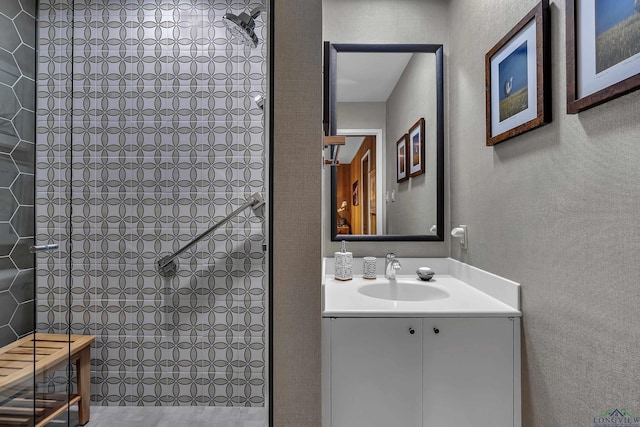 bathroom with vanity, a textured wall, and tiled shower