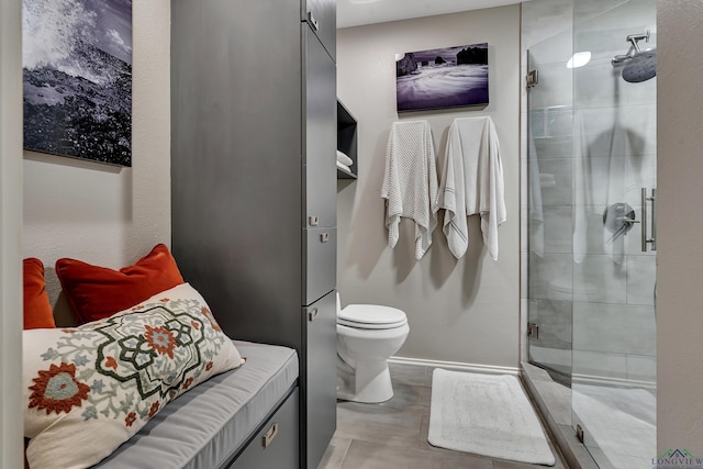 full bath with toilet, baseboards, and a stall shower