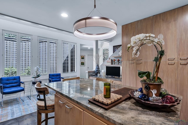 kitchen featuring recessed lighting, brown cabinetry, and dark stone countertops