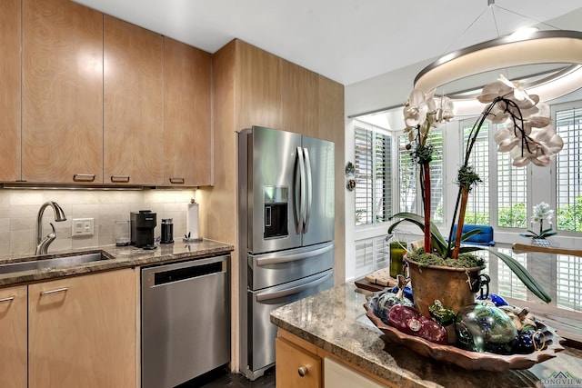 kitchen featuring a sink, dark stone counters, tasteful backsplash, and stainless steel appliances