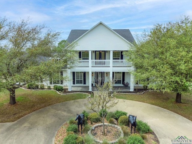 view of front facade with covered porch, a balcony, and a front lawn