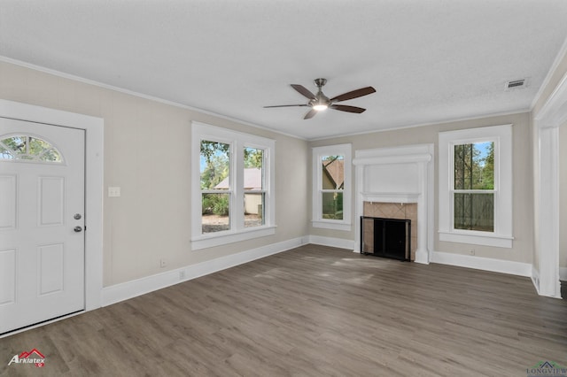 unfurnished living room featuring a healthy amount of sunlight, dark hardwood / wood-style floors, and ornamental molding