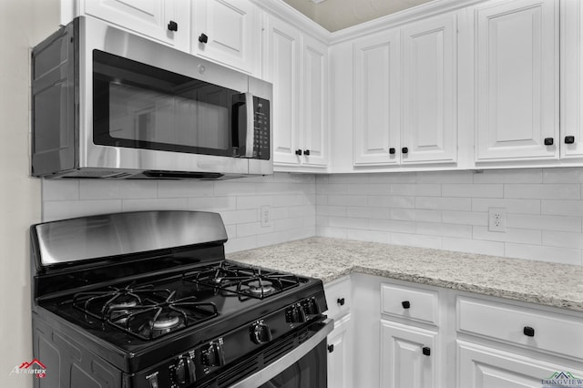 kitchen featuring black gas range, decorative backsplash, and white cabinetry