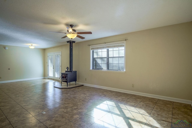 unfurnished living room featuring ceiling fan, a wood stove, and a textured ceiling