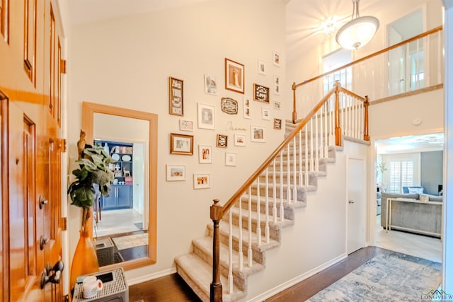 staircase featuring wood-type flooring, a high ceiling, and heating unit