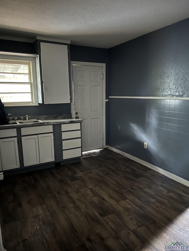 kitchen featuring white cabinets, a textured ceiling, dark wood-type flooring, and sink