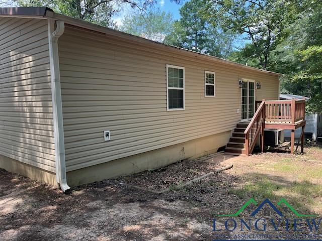 view of side of property with a wooden deck and cooling unit