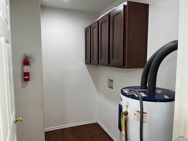 laundry area with water heater, hookup for a washing machine, cabinets, and wood-type flooring