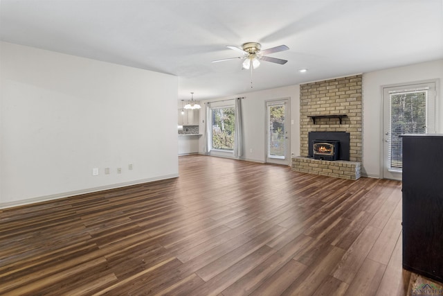 unfurnished living room featuring dark hardwood / wood-style floors, ceiling fan with notable chandelier, and a wealth of natural light