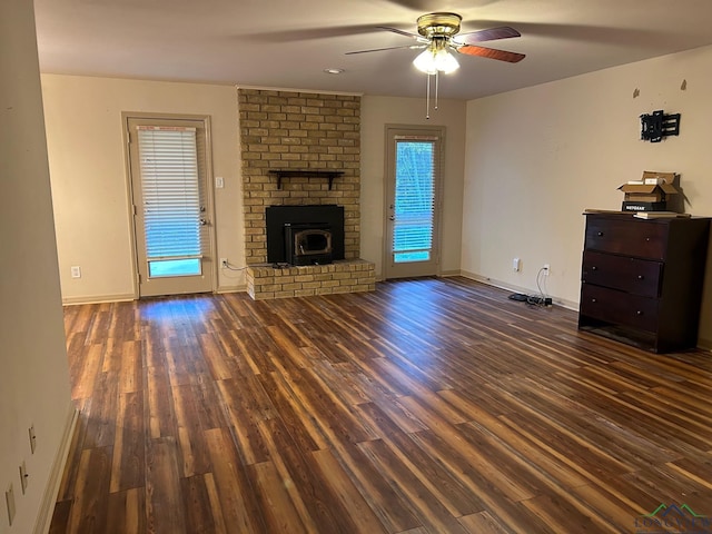 unfurnished living room with a wood stove, ceiling fan, and dark hardwood / wood-style floors