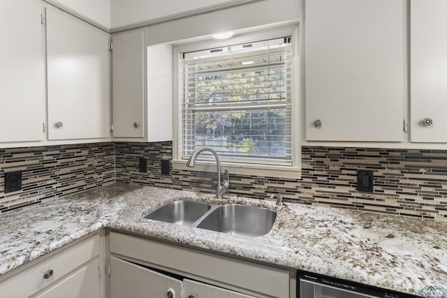 kitchen with white cabinets, stainless steel dishwasher, light stone countertops, and sink