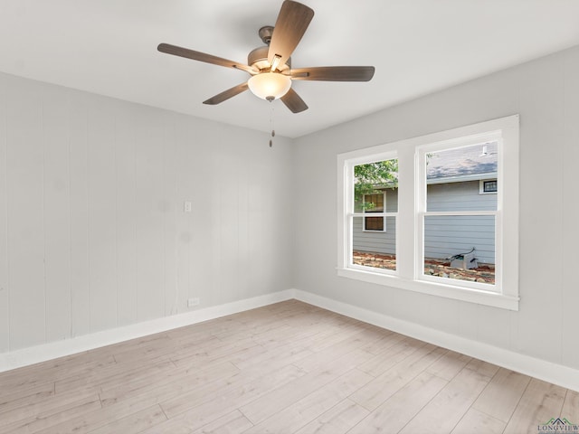 spare room with baseboards, light wood-style flooring, and a ceiling fan