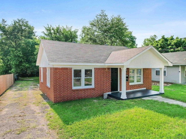 ranch-style home featuring a shingled roof, fence, a front lawn, and brick siding