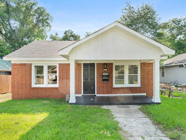 view of front of house with brick siding, a front lawn, and covered porch
