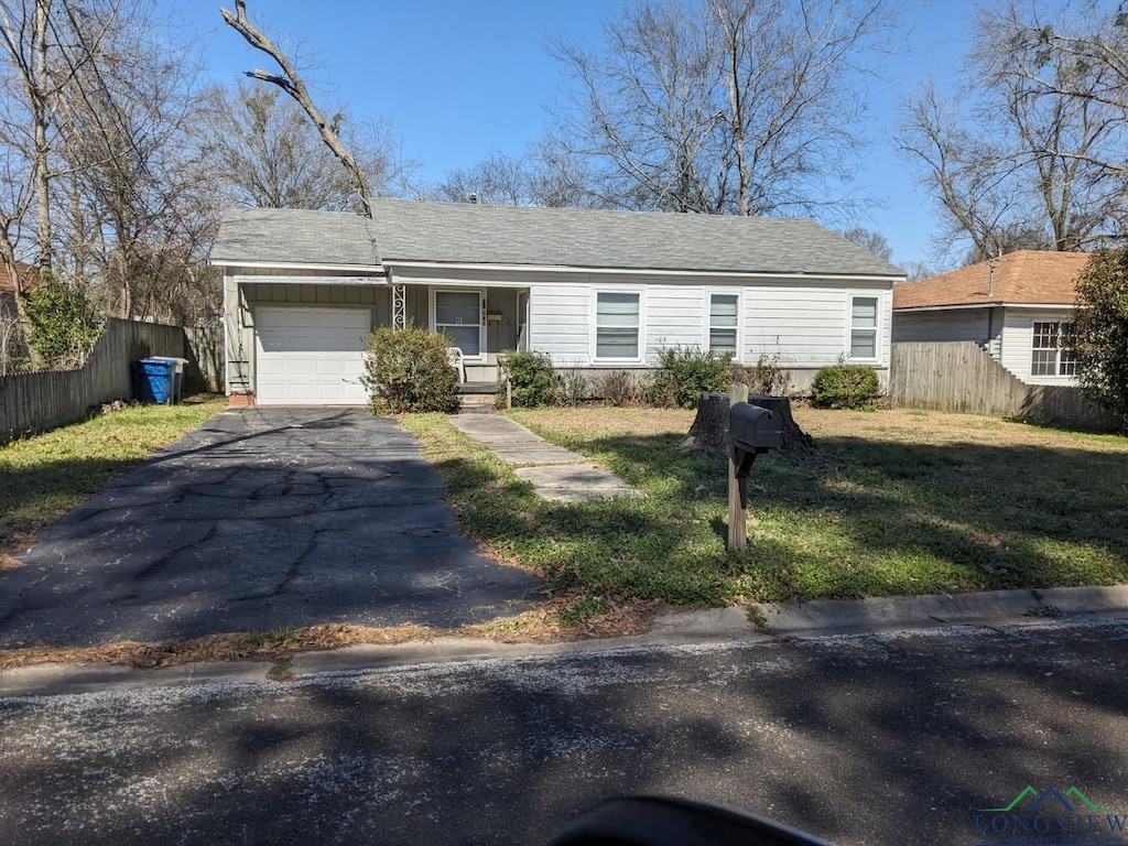 view of front of house featuring aphalt driveway, a shingled roof, fence, a garage, and a front lawn