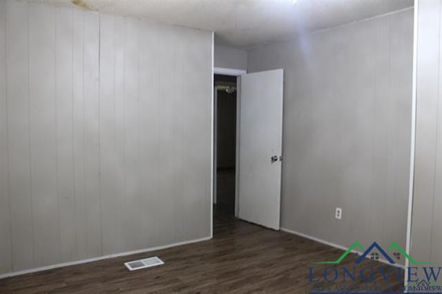 empty room featuring wood walls and dark hardwood / wood-style flooring