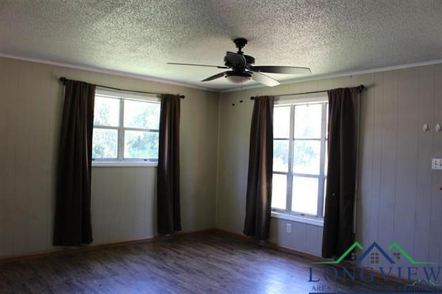 empty room featuring ceiling fan, wood-type flooring, ornamental molding, and wooden walls