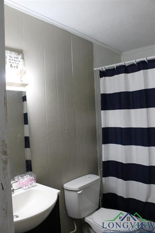 bathroom with a shower with shower curtain, toilet, sink, and crown molding