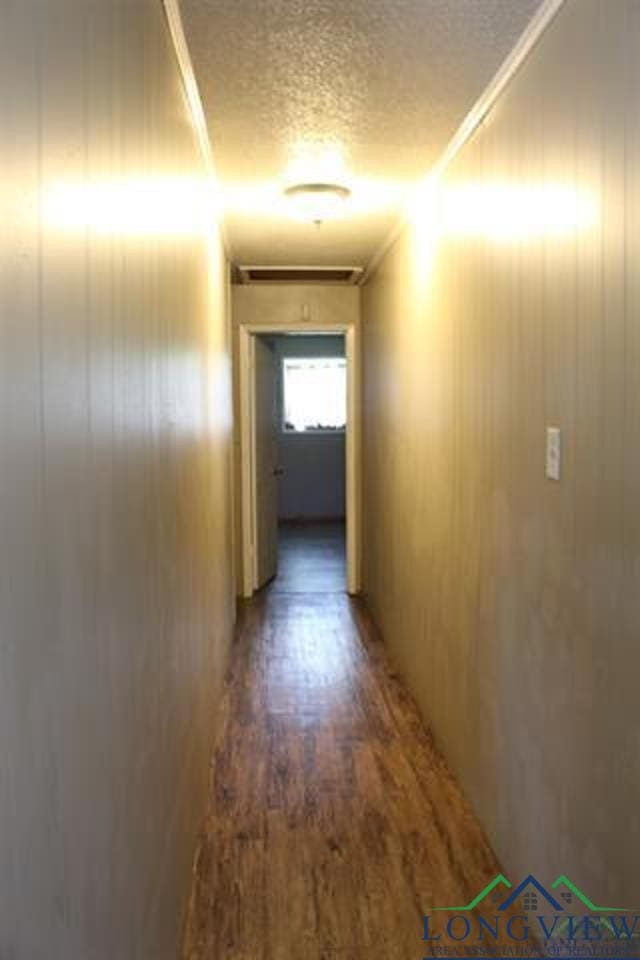 hall featuring crown molding, wooden walls, and dark wood-type flooring