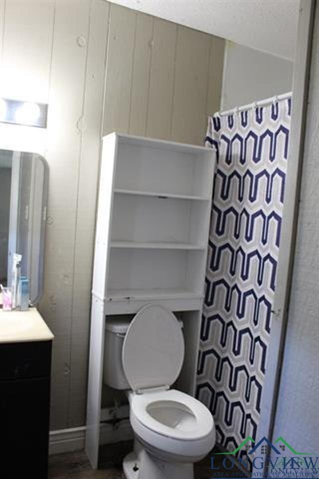 bathroom featuring a shower with shower curtain, vanity, and toilet