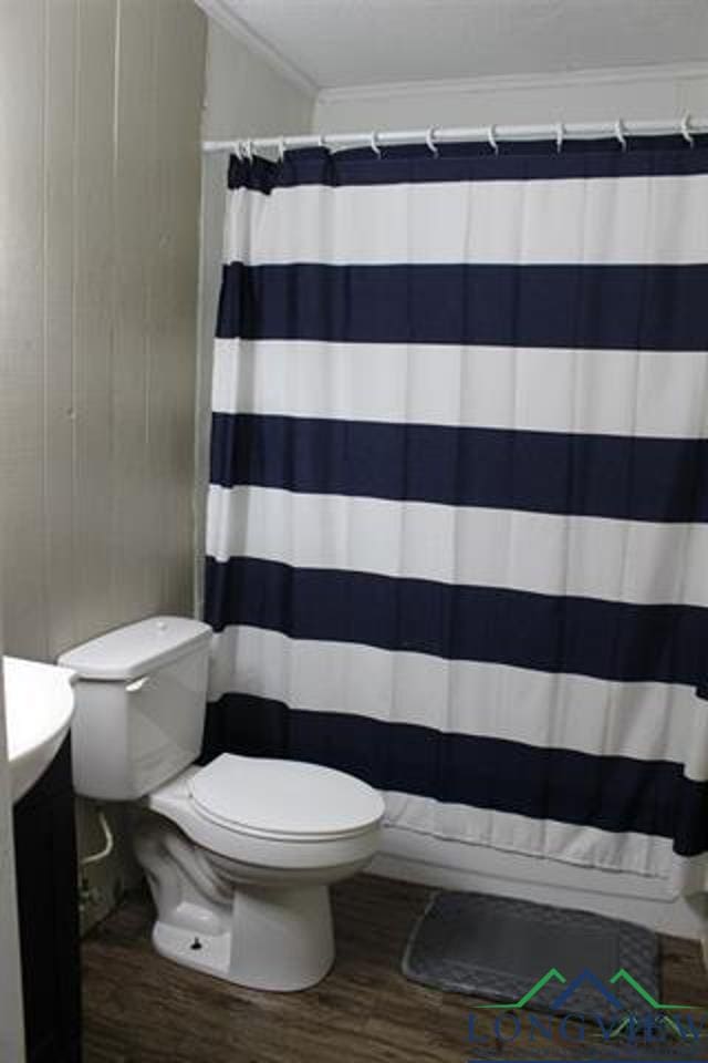 bathroom featuring hardwood / wood-style flooring, toilet, walk in shower, and ornamental molding