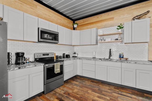 kitchen with dark wood-type flooring, sink, white cabinetry, light stone counters, and appliances with stainless steel finishes