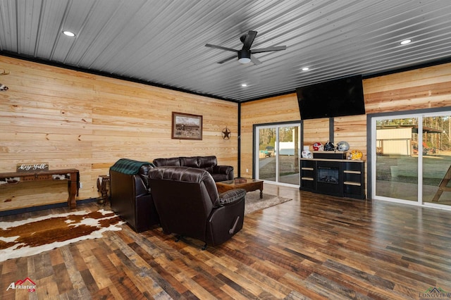 living room with ceiling fan, dark wood-type flooring, wooden ceiling, and wooden walls