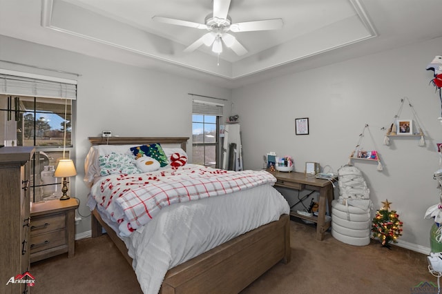 carpeted bedroom featuring a tray ceiling and ceiling fan