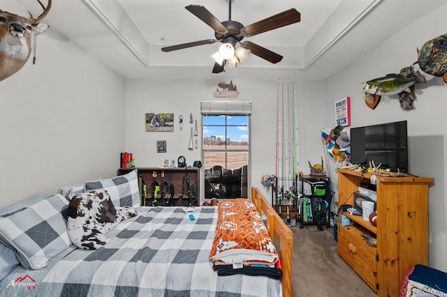 carpeted bedroom featuring a tray ceiling and ceiling fan