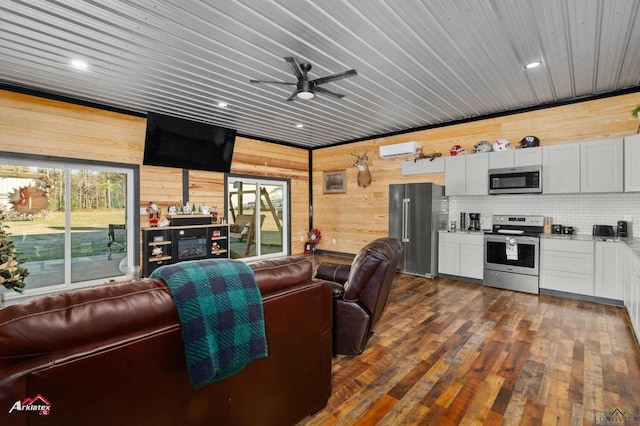 living room featuring ceiling fan, wooden walls, dark hardwood / wood-style flooring, and a wood stove